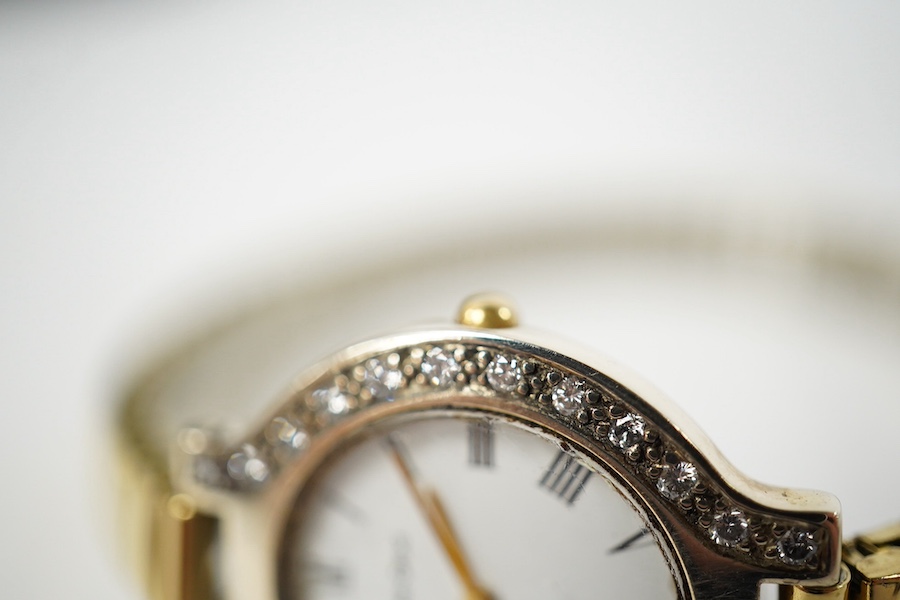 A lady's modern 9kt Bueche Girod quartz wrist watch, with diamond set bezel, case diameter 25mm, on a steel and gold plated flexible bracelet (detached), with Bueche Girod box. Condition - poor to fair